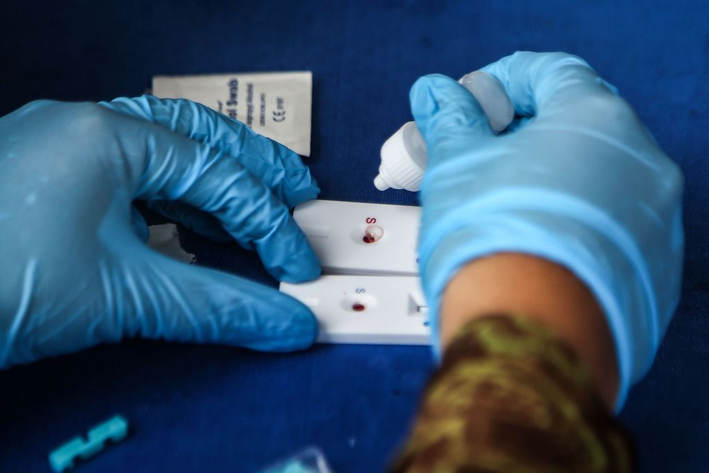 Petugas mengambil sampel darah untuk tes cepat antibodi secara gratis di pos pengamanan Natal dan Tahun Baru, Pamulang, Tangerang Selatan, Banten, Jumat (25/12/2020). 