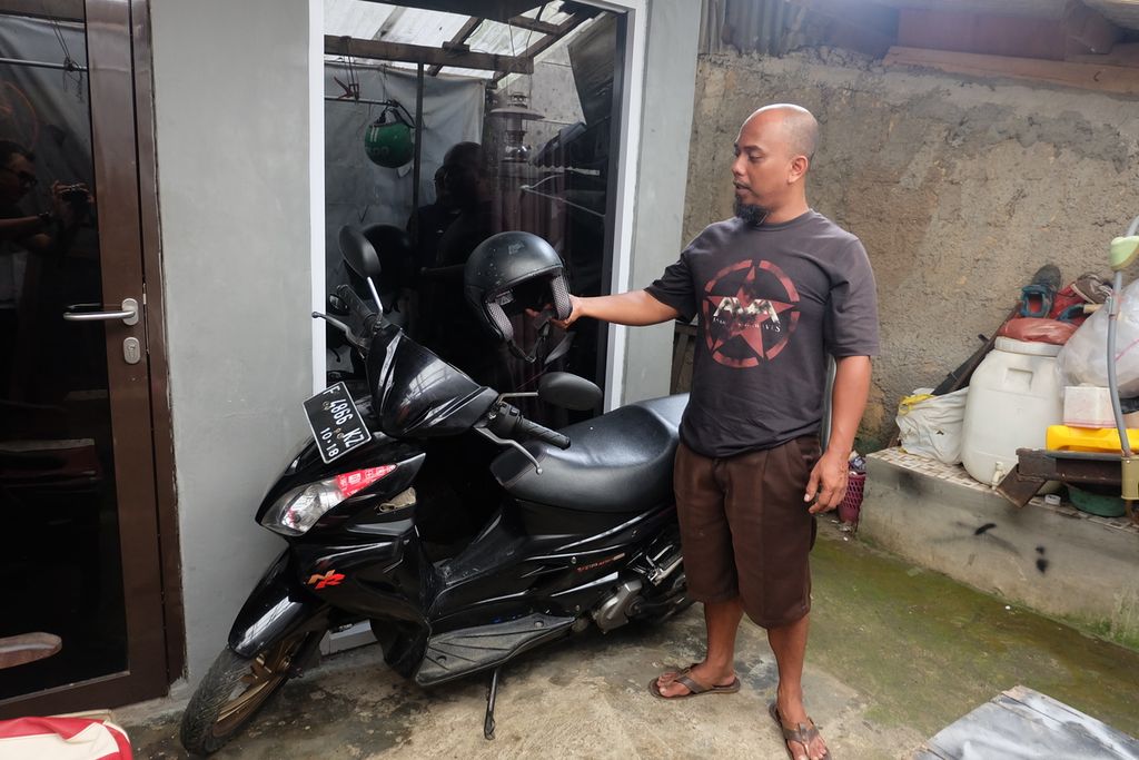 Ade Mulyana Setiawan (42) dan sepeda motor Suzuki Skywave miliknya di rumahnya di Harjasari, Kecamatan Bogor Selatan, Kota Bogor, Kamis (20/10/2022). Motor ini dibelinya setelah menjual kendaraan roda dua sebelumnya, Honda Beat Street, yang pada 2019 diduga kuat kemasukan oli palsu. Sejumlah komponen mesin Honda Beatnya waktu itu rusak beberapa hari setelah ganti oli di salah satu bengkel di Ciomas, Bogor.