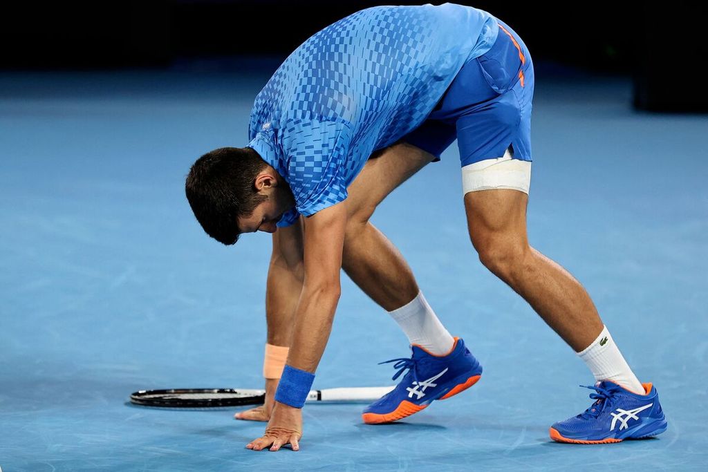 Petenis Serbia Novak Djokovic menahan rasa sakit saat melawan petenis Bulgaria Grigor Dimitrov pada babak ketiga Australia Terbuka di Rod Laver Arena, Melbourne, Sabtu (21/1/2023). Djokovic menang dengan skor 7-6 (7), 6-3, 6-4. 