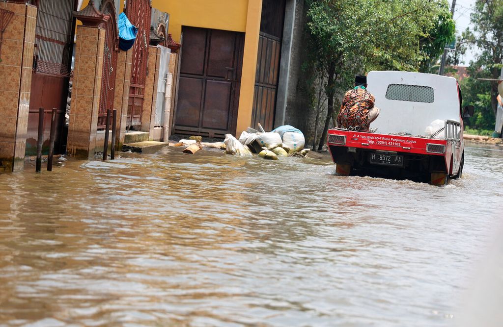 Warga menumpang kendaraan bak terbuka saat melintasi banjir di Desa Karangrowo, Kecamatan Undaan, Kabupaten Kudus, Jawa Tengah, Jumat (17/3/2023). Sedimentasi beberapa sungai dinilai menjadi salah satu penyebab banjir di sejumlah wilayah pantura timur Jateng.  