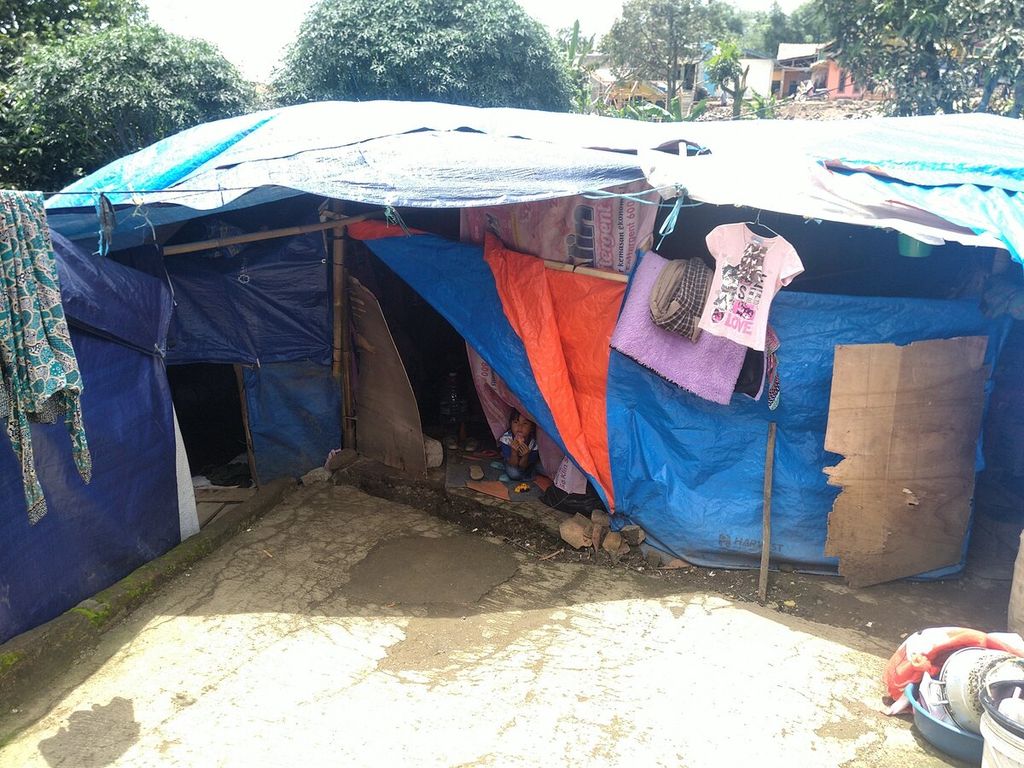 Anak penyintas gempa cianjur masih tinggal di dalam tenda terpal di Kampung Sindangpalay, Cugenang, Kabupaten Cianjur, Jawa Barat, Jumat (6/1/2023). Hingga saat ini, warga masih menunggu kepastian pemberian bantuan pembangunan rumah terdampak gempa.