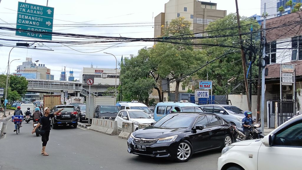 Seorang ”pak ogah” di Jalan Palmerah Utara, Jakarta Barat, saat mengarahkan kendaraan yang putar balik, Jumat (10/2/2023). Plang rambu dilarang belok dan putar balik tak diindahkan sehingga kerap menimbulkan kemacetan.