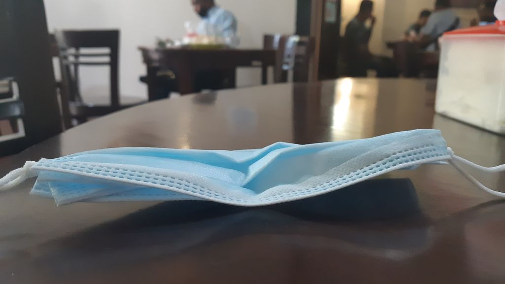 Masker diletakan di atas meja di dalam salah satu rumah kopi di Ambon, Maluku, pada Selasa (12/1/2020). Banyak pengunjung rumah kopi mengabaikan protokol Covid-19.