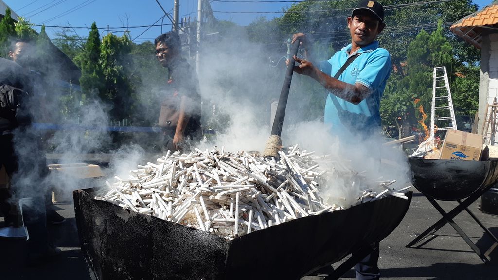 Pekerja berupaya membakar rokok ilegal. Sebanyak 27 karton rokok tanpa pita cukai yang diperoleh dari pengungkapan kasus perdagangan rokok ilegal dimusnahkan oleh Kejaksaan Negeri Sidoarjo, Rabu (22/6/2022).