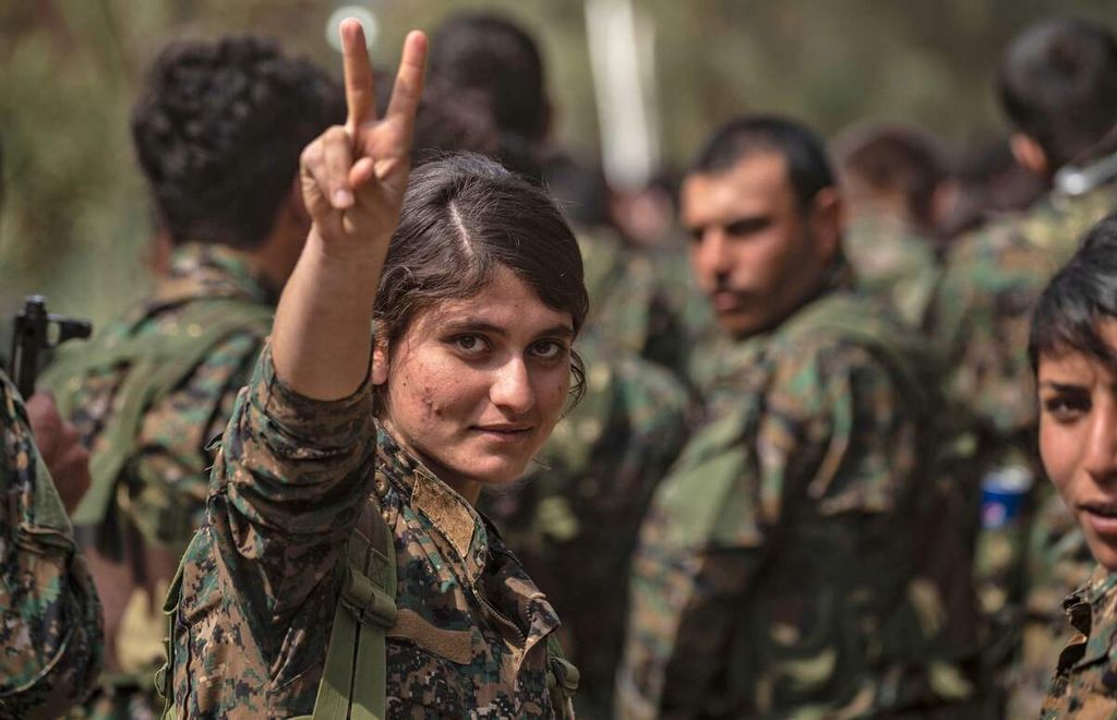 Seorang perempuan petempur anggota milisi Pasukan Demokratik Suriah (SDF) Kurdi dukungan AS mengacungkan isyarat tangan berisi pesan "kemenangan (<i>victory</i>)" di dekat ladang minyak Omar di Provinsi Deir Ezzor, Suriah timur, 23 Maret 2019. 