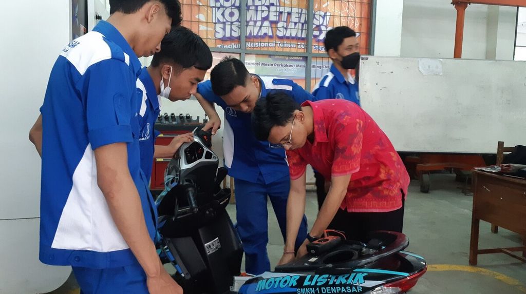 Putu Agus Saskara Yoga (kanan) mendampingi siswa SMK Negeri 1 Denpasar dalam praktik konversi sepeda motor ke mesin listrik di SMK Negeri 1 Denpasar, Senin (24/10/2022).