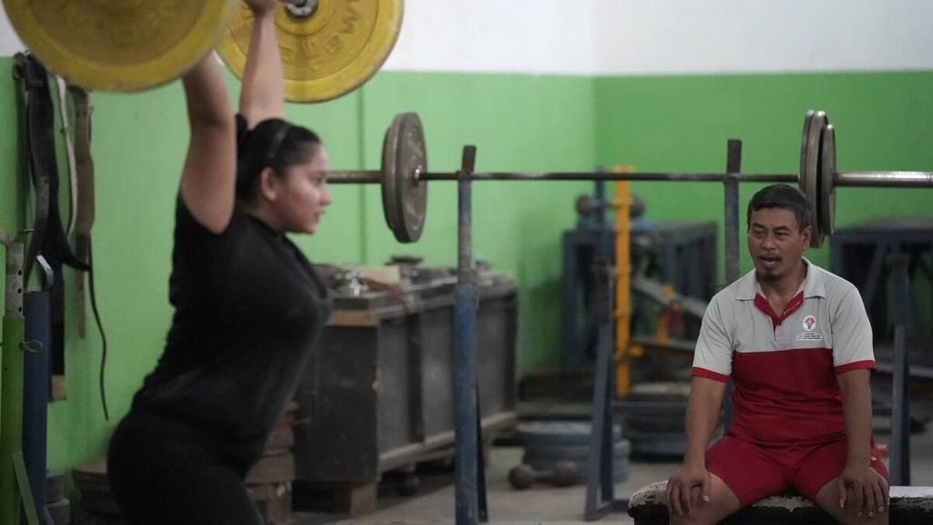 Asisten pelatih angkat besi Indonesia, Minan, memberikan instruksi kepada lifter Sukma Apriyani (kelas 76 kilogram) yang menjalani pemusatan latihan daerah PON 2020 cabang angkat besi Jawa Barat di Gedung Kesegaran Jasmani, Kota Bekasi, Jawa Barat, Jumat (3/7/2020). 