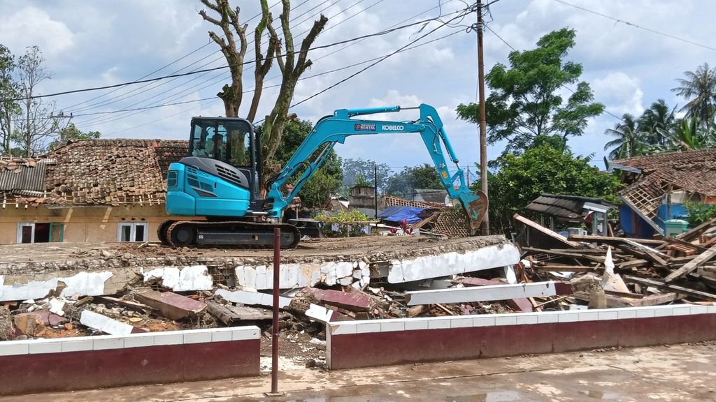 Alat berat digunakan untuk membersihkan area dari puing-puing runtuhan bangunan Sekolah Dasar Negeri Sukamaju 1, Kampung Pangkalan, Desa Benjot, Kecamatan Cugenang, Cianjur, Kamis (8/12/2022). 