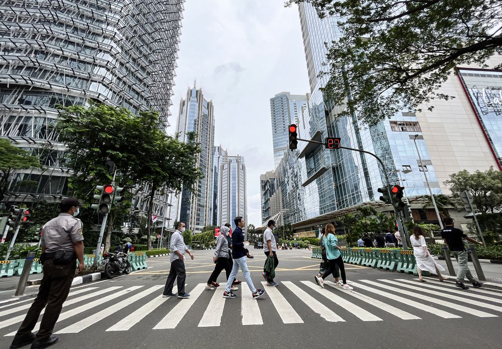 Karyawan menyeberang jalan saat jam istirahat di Sudirman Central Business District (SCBD), Jakarta Selatan, awal Januari 2023.  