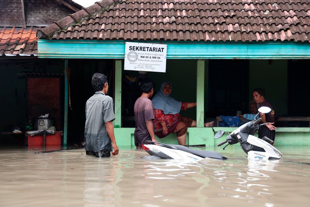 Warga  memastikan tetangganya yang salah satu penghuninya lanjut usia untuk dapat dievakuasi dari rumahnya yang terendam banjir di Kelurahan Joyotakan, Kecamatan Serengan, Kota Surakarta, Jawa Tengah, Jumat (17/2/2023). Banjir yang terjadi sejak Kamis sore terus bertambah tinggi seiring meluapnya beberapa sungai, salah satunya Bengawan Solo. Sebagian warga yang rumahnya terendam banjir setinggi 60 sentimeter hingga 150 sentimeter mengungsi ke sejumlah tempat, antara lain gereja, masjid, dan sekolah.