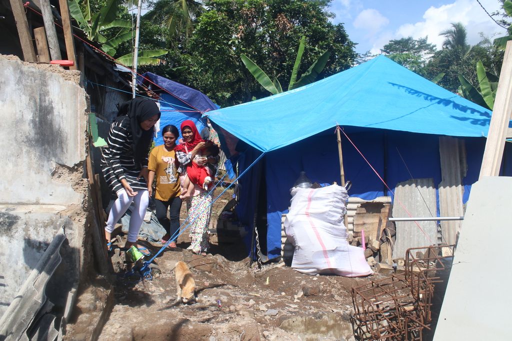 Sejumlah warga melewati tenda darurat di Kampung Sedong Kulon, Kelurahan Bojongherang, Kecamatan Cianjur, Kabupaten Cianjur, Jawa Barat, Sabtu (21/1/2023). Puluhan warga di wilayah ini masih tidur di tenda-tenda karena bangunan mereka rusak parah dan tidak layak ditinggali.