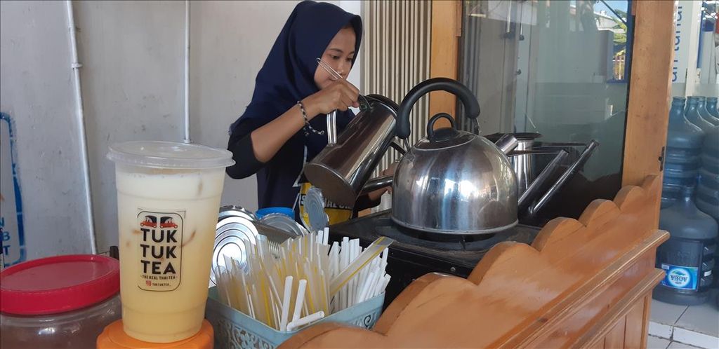 Penjual Tuk Tuk Tea membuat segelas Teh Thailand dari gelas plastik di Banyuwangi, Selasa (6/8/2019). Usaha waralaba minuman Tuk Tuk Tea telah menyiapkan 1.000 botol minum atau <i>tumbler </i>untuk para penggemarnya sebagai usaha mengurangi sampah plastik.