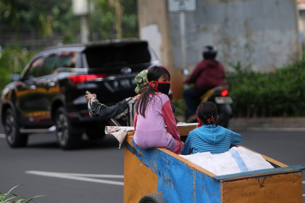 Keluarga pemulung berkeliling di kawasan Kuningan, Jakarta Selatan, dengan gerobak untuk mengumpulkan barang bekas, Minggu (10/5/2020). 
