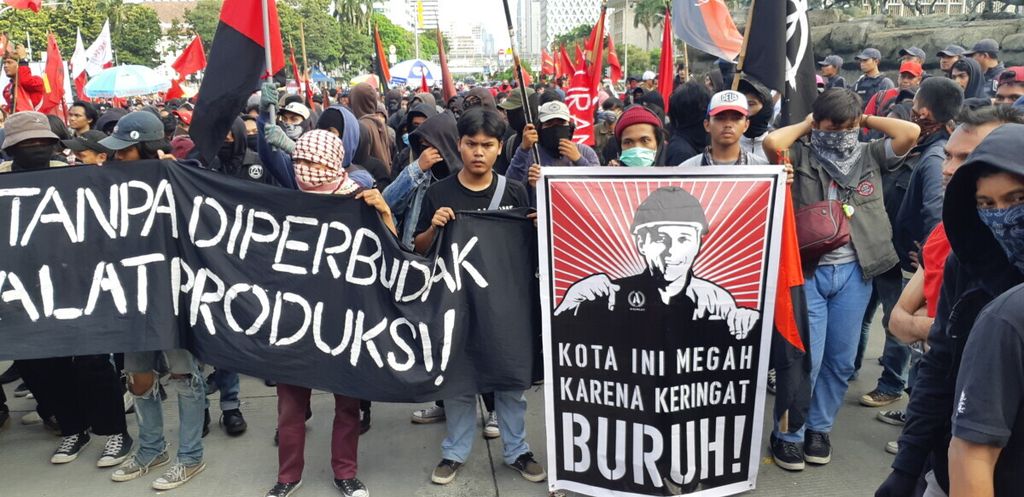 Kumpulan massa dari berbagai serikat buruh dan mahasiswa berorasi di samping Patung Arjuna Wijaya, Jakarta, Rabu (1/5/2019), untuk memperingati Hari Buruh Internasional 2019. Mereka menuntut penghapusan PP No 78 Tahun 2015.