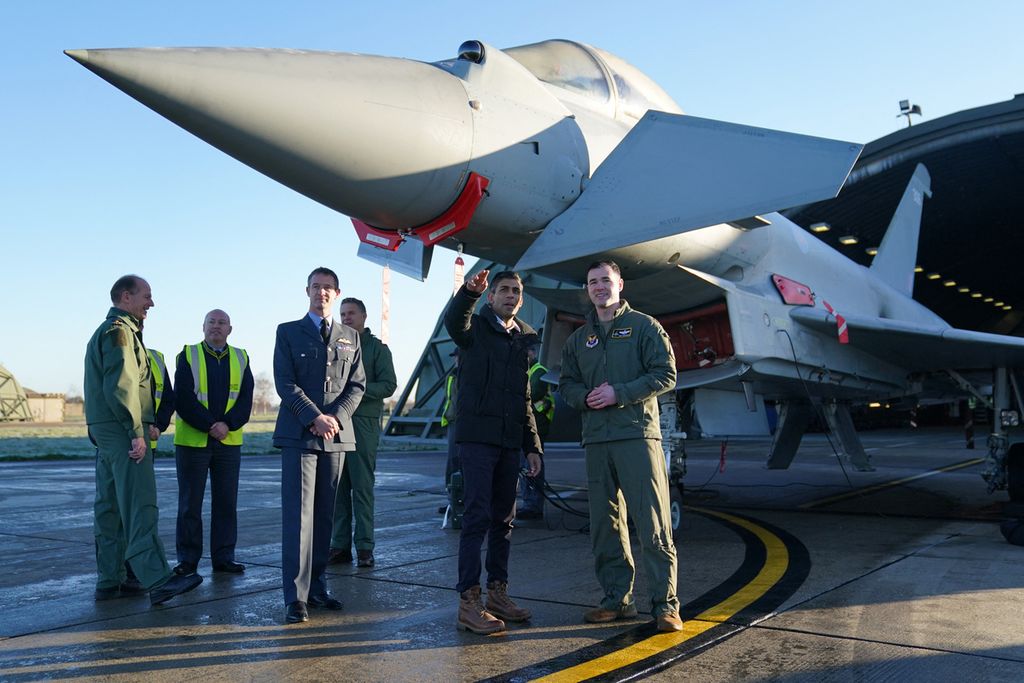 Perdana Menteri Inggris Rishi Sunak (dua dari kanan) berdiri di depan sebuah jet tempur Inggris Typhoon, bersama sejumlah pejabat militer di Pangkalan Udara Militer RAF COningsby, Lincoln, Inggris Timur, Jumat (9/12/2022). Inggris, bersama Jepang dan Italia sepakat untuk mengembangkan jet tempur bersama dan diharapkan bisa mengudara pada tahun 2035. Inggris berharap jet tempur siluman baru bermesin ganda itu akan menggantikan peran Typhoon. (Photo by Joe Giddens / POOL / AFP)