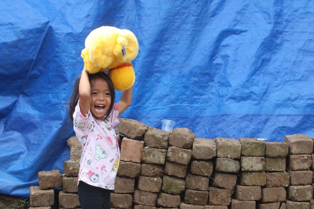 Salah satu anak bergembira setelah mendapatkan boneka yang berasal dari kegiatan amal Yayasan Dana Kemanusiaan Kompas bersama sejumlah pihak di Kampung Sedong Kulon, Kelurahan Bojongherang, Kecamatan Cianjur, Kabupaten Cianjur, Jawa Barat, Sabtu (21/1/2023).