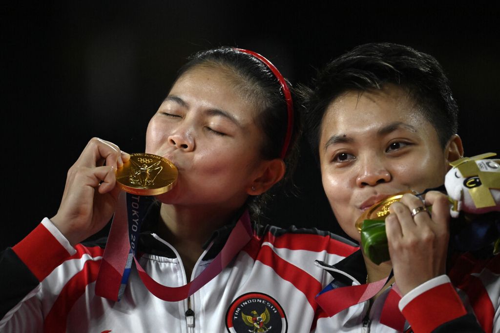 Pasangan Indonesia, Greysia Polii dan Apriyani Rahayu, berpose dengan medali emas yang berhasil mereka peroleh dalam final ganda putri bulu tangkis Olimpiade Tokyo 2020.