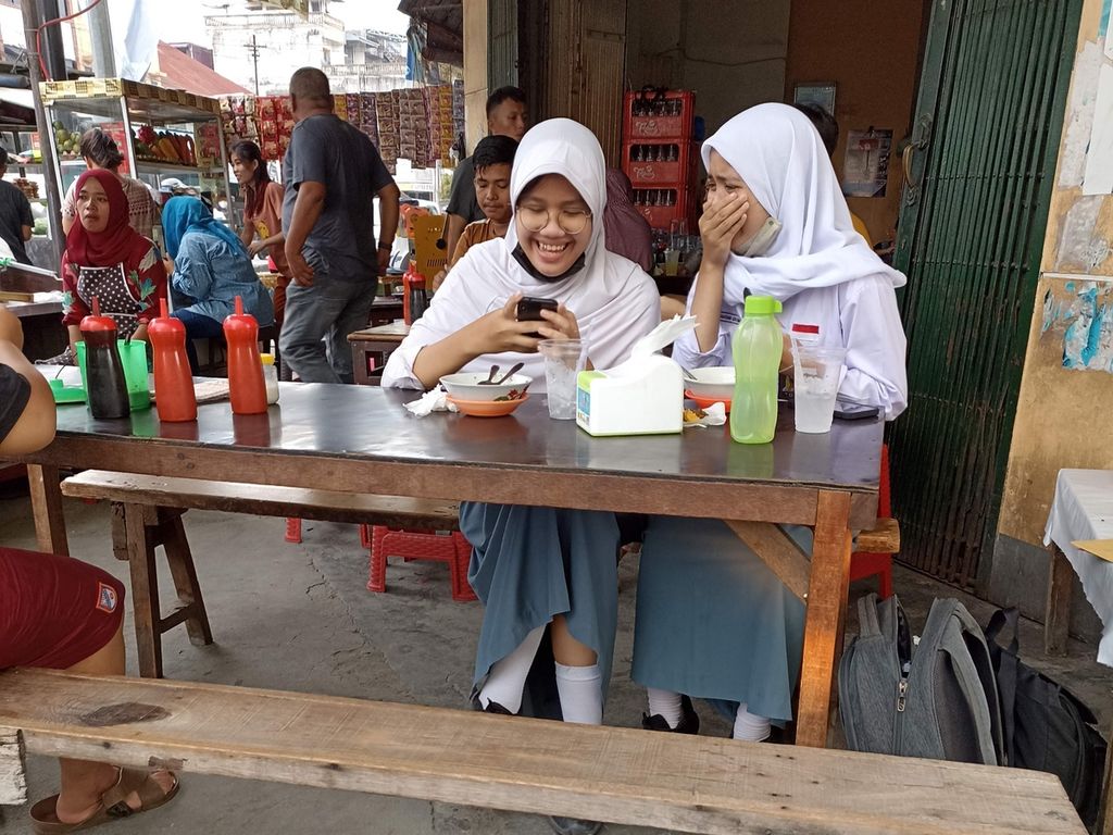 Siswi SMA beraktivitas di sebuah rumah makan di Jalan Iskandar Muda, Medan, Sumatera Utara, Selasa (2/8/2022). Di tengah peningkatan kasus baru Covid-19, Kota Medan meningkatkan protokol kesehatan dengan kriteria PPKM level I. 