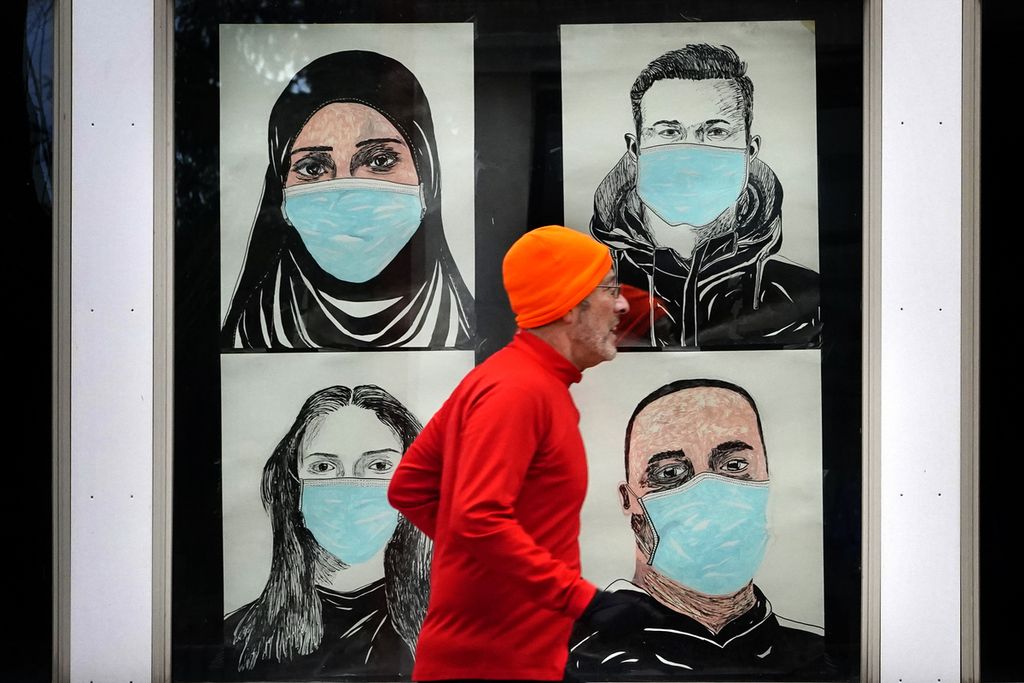 Seorang pelari melewati jendela yang menampilkan potret orang-orang yang memakai masker untuk membantu mencegah penyebaran virus korona di Lewiston, Maine, AS, Senin (16/11/2020). 