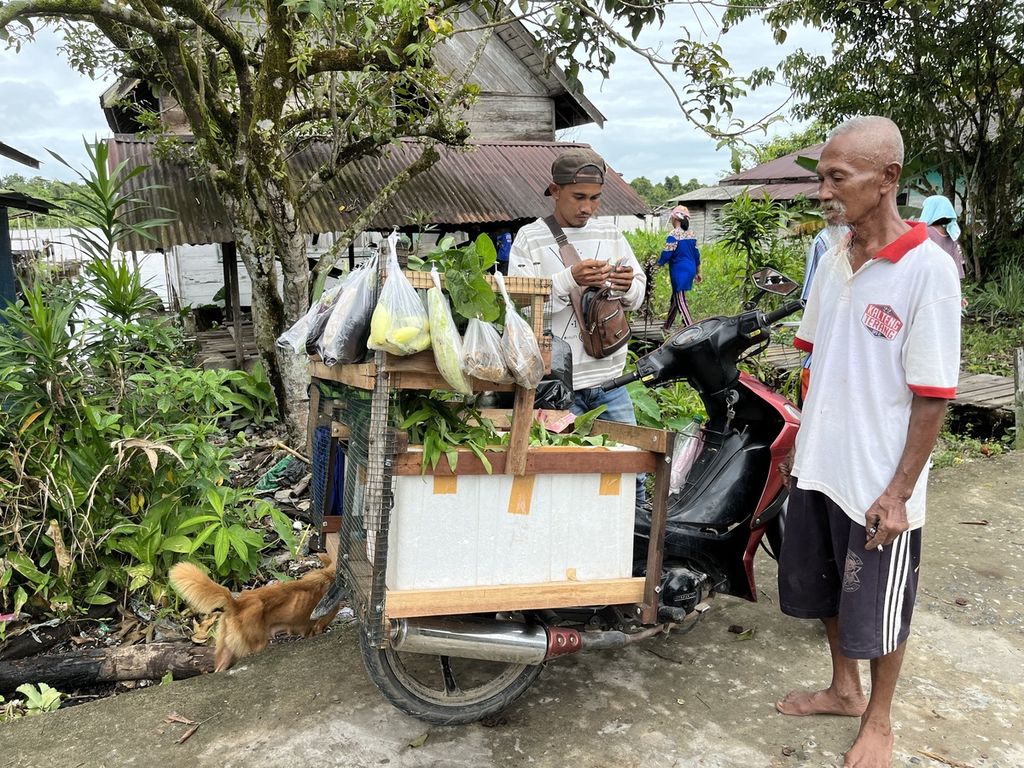 Warga Desa Kalumpang, Kecamatan Mantangai, Kabupaten Kapuas, membeli sayur dari pedagang keliling, warga transmigran atau biasa dipanggil paman sayur, pertengahan Agustus 2022. 