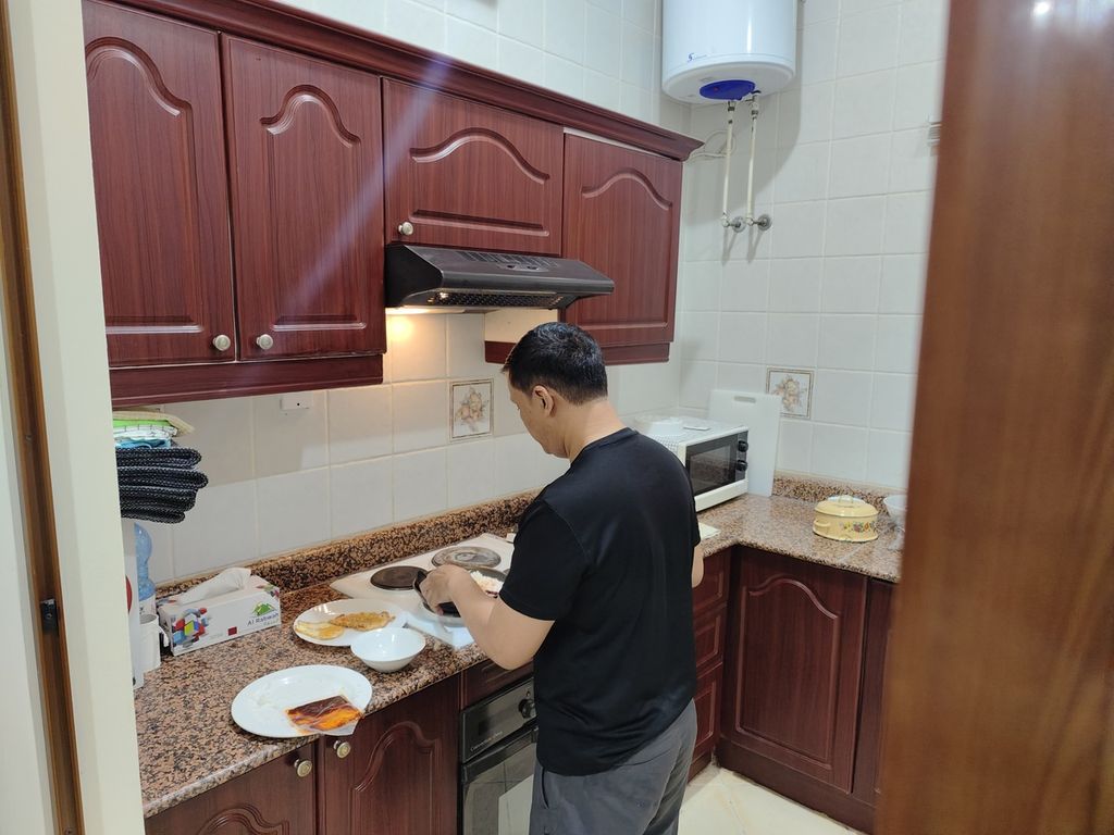 Pewarta foto <i>Kompas,</i> Yuniadhi Agung, saat memasak di apartemen sebelum berangkat liputan Piala Dunia Qatar 2022.