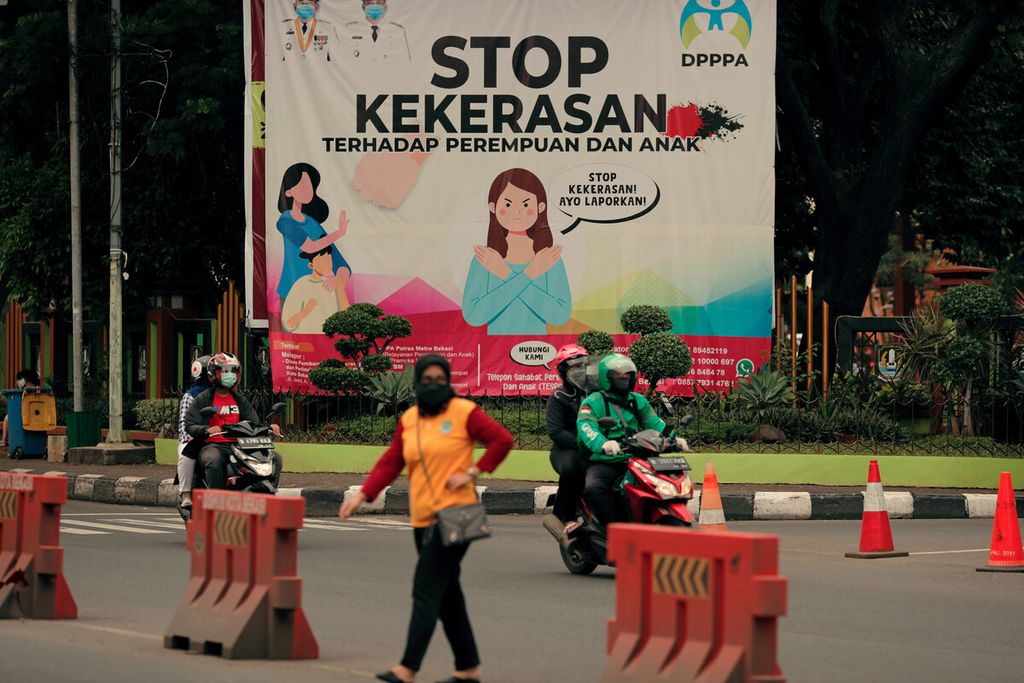 Warga melintasi baliho ajakan untuk menghentikan kekerasan terhadap perempuan dan anak di pintu masuk Kantor Wali Kota Bekasi, Jawa Barat, Rabu (23/6/2021). 