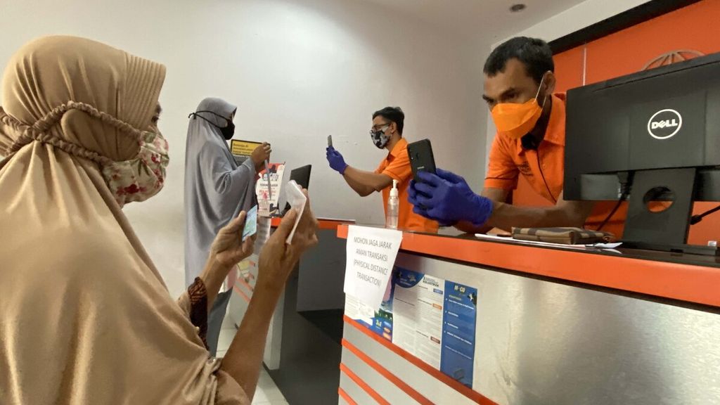 Petugas memotret warga dengan uang yang ia peroleh dari pencairan bantuan sosial (bansos) tunai di Kantor Pos Kecamatan Curug, Kabupaten Tangerang, Banten, Sabtu (25/4/2020).