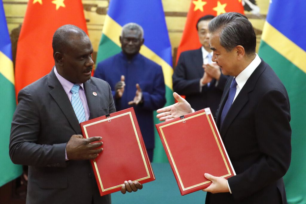 Menteri Luar Negeri China Wang Yi (kanan), dan Menteri Luar Negeri Kepulauan Solomon, Jeremiah Manele hendak berjabat tangan mengiringi pertukaran dokumen kerja sama yang telah ditandatangani di Balai Agung Rakyat di Beijing pada Rabu (9/10/2019).