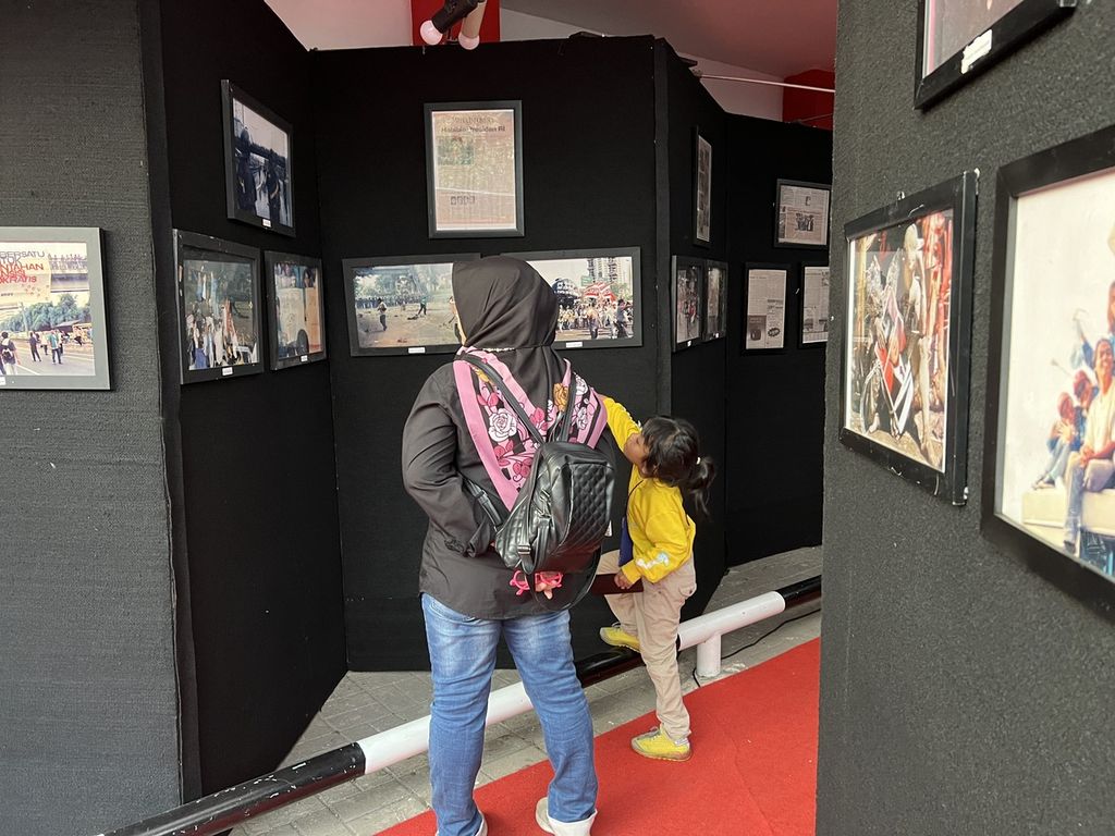 Seorang anak dan ibu, pengunjung tengah menyaksikan pameran foto bertajuk<i> 25 Tahun Reformasi</i>. Pameran ini diselenggarakan Pena 98 dari 11-17 Mei 2023.