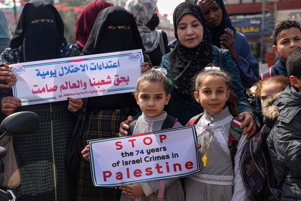 Warga Palestina membentangkan poster saat berdemonstrasi untuk menggalang dukungan internasional terhadap perjuangan Palestina melawan Israel di kamp pengungsi Rafah di selatan Jalur Gaza, Senin (7/3/2022). Mereka mengharapkan dukungan internasional seperti Ukraina yang sedang berjuang melawan serangan Rusia. 
