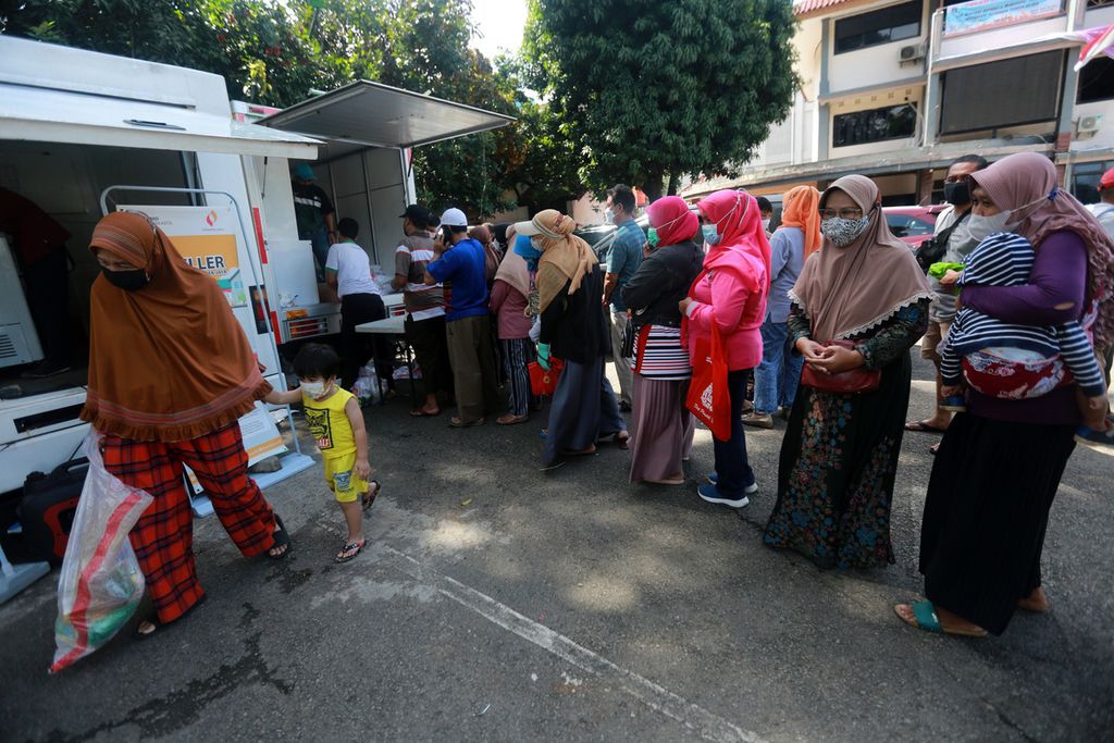 Seorang ibu kelluar dari antrean setelah membeli bahan makanan saat badan usaha milik daerah, PT Food Station Tjipinang Jaya, menggelar penjualan pangan murah di halaman kantor Kelurahan Pondok Kelapa, Kecamatan Duren Sawit, Jakarta Timur, Rabu (2/3/2022). 