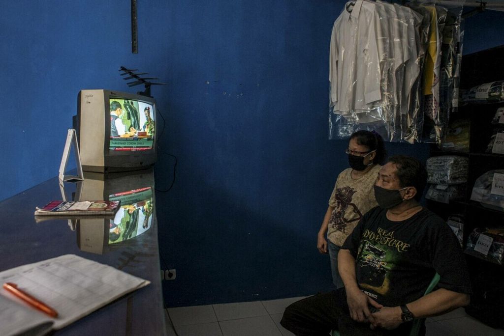Warga menonton televisi yang menayangkan langsung penyuntikan vaksin CoronaVac perdana di Jakarta, Rabu (13/1/2021). 