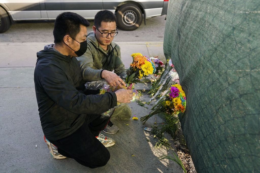 Dua pria meletakkan bunga di dekat Studio Tari Star Dance untuk menghormati para korban yang tewas dalam penembakan massal di Monterey Park, California, 22 Januari 2023. Pria bersenjata melepaskan tembakan dan menewaskan 11 orang serta melukai sembilan orang lainnya. 