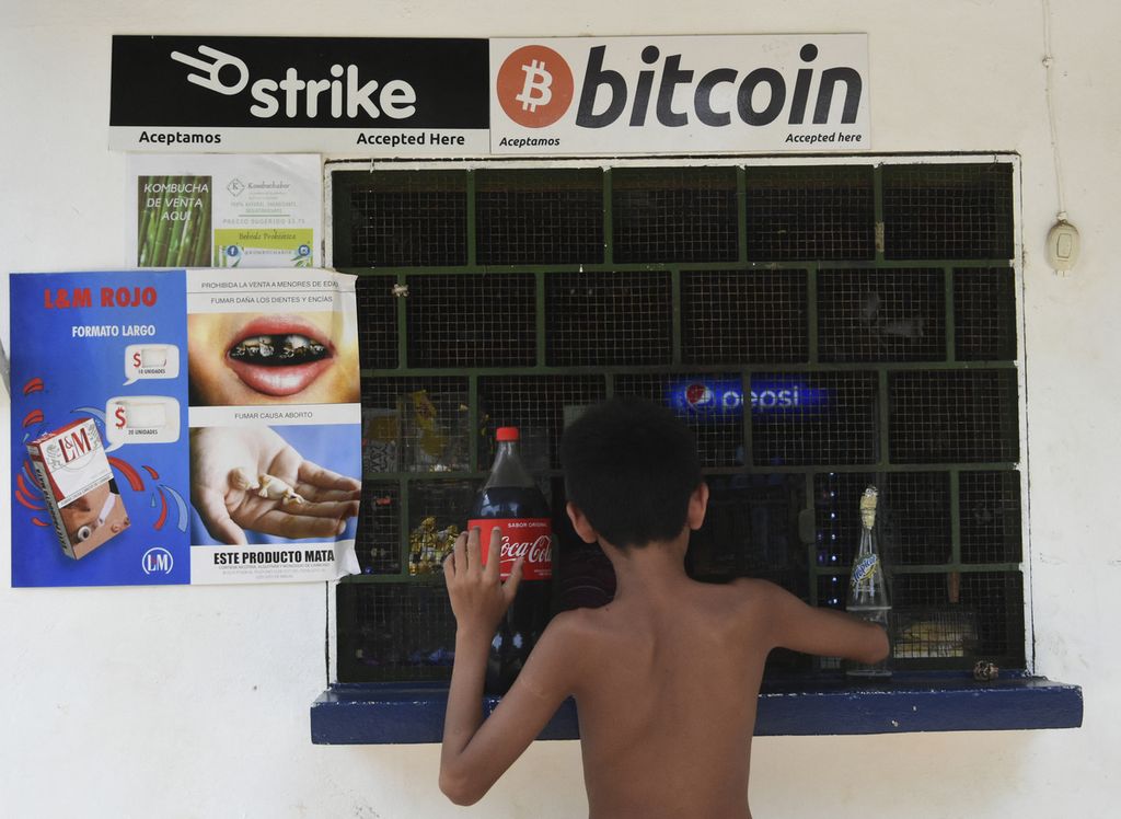 Seorang anak membeli di toko yang menerima bitcoin di San Salvador, El Savador, Rabu (9/6/2021) waktu setempat. (Photo by Stanley ESTRADA / AFP)