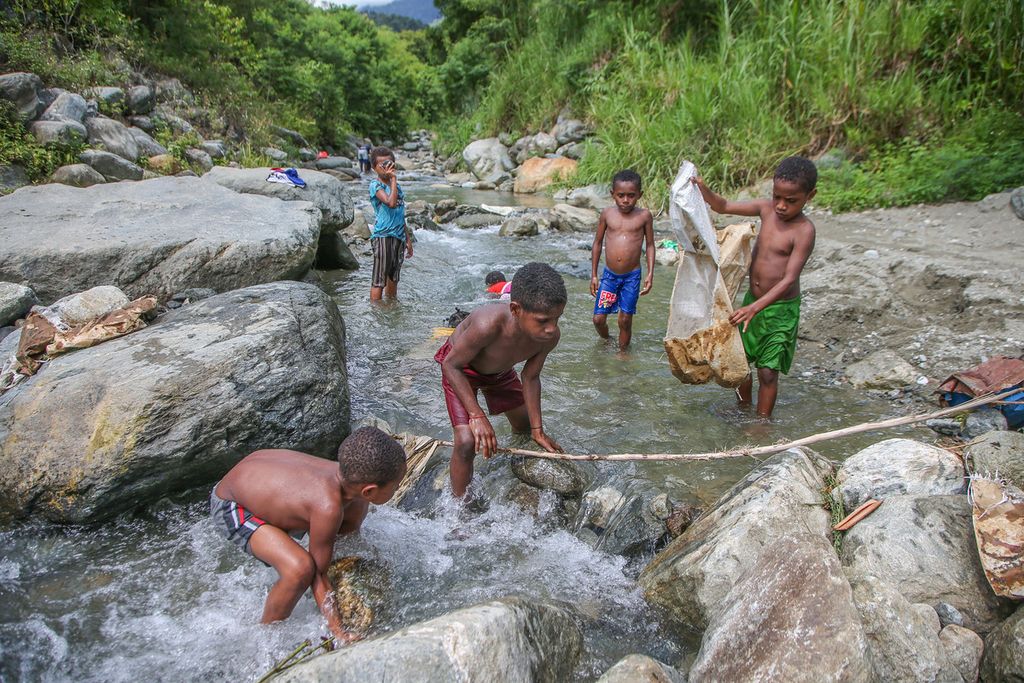 Anak-anak bermain di Sungai Dobokurung yang berhulu di cagar alam Pegunungan Cycloop melintasi kawasan Doyo Baru, Sentani, Jayapura, Minggu (28/11/2021). Pada tahun 2019, terjadi banjir bandang di sungai Dobokurung yang menyebabkan 105 orang tewas dan kerugian mencapai Rp 506 miliar. 