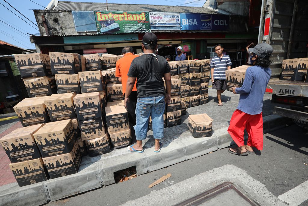 Warga menata kardus bantuan sosial Pemprov DKI yang diturunkan dari truk ekspedisi di Kelurahan Bidara Cina, Kecamatan Jatinegara, Jakarta Timur, Senin (27/7/2020). 