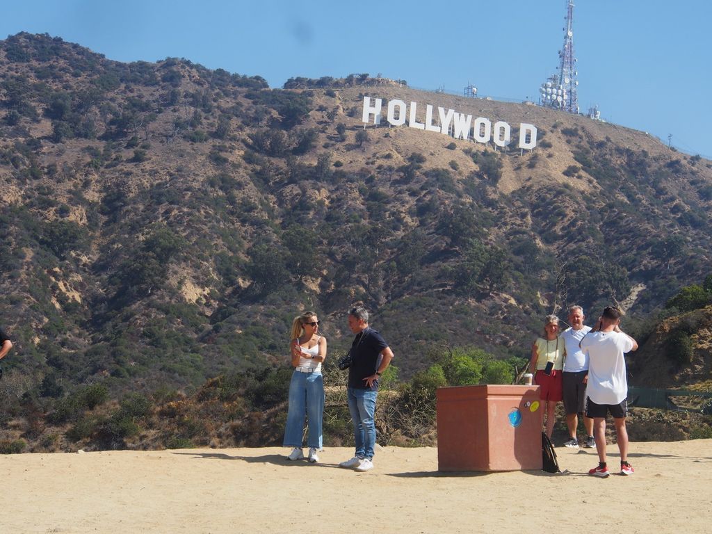 Sejumlah wisatawan mengabadikan momen saat berada di Hollywood Hills, Pegunungan Santa Monica, California, Amerika Serikat, dengan latar belakang markah Hollywood yang terkenal, Senin (29/8/2022). Markah ini menghadap ke Distrik Hollywood Los Angeles. Awalnya markah Hollywood adalah media promosi untuk pengembangan kawasan perumahan baru tahun 1923 silam. Belakangan seiring berkembang pesatnya industri film Amerika Serikat, markah ini menjadi semacam penanda produk budaya populer seiring kemunculannya dalam film-film produksi Hollywood.