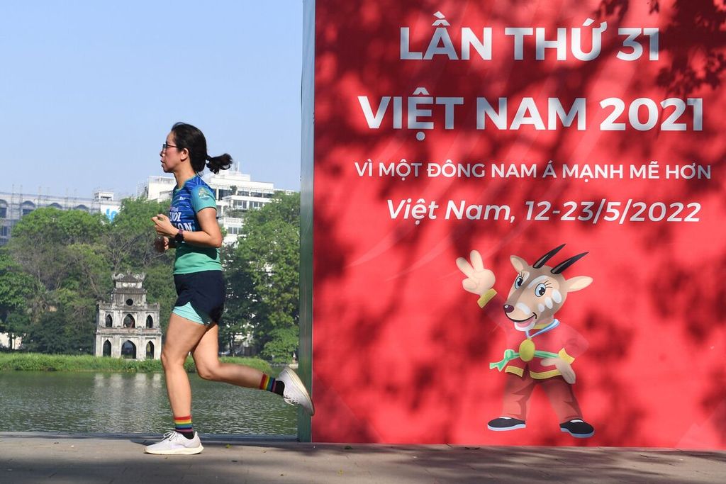 Seorang pelari melintasi reklame SEA Games Vietnam 2021, 4 Mei 2022 lalu, di Hanoi. Pesta olahraga terbesar se-Asia Tenggara itu akan dibuka pada 12 Mei mendatang. 