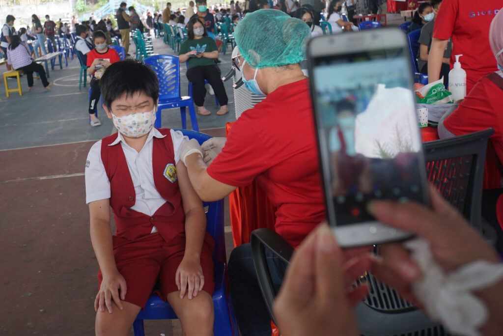 Gavrie (12), siswa SD Eben Haezar Manado, meringis menahan sakit ketika disuntik vaksin Sinovac untuk Covid-19 pada hari pertama vaksinasi untuk anak di Manado, Sulawesi Utara, Senin (5/7/2021). Pemprov Sulut menarget 100.000 siswa di Sulut bisa tervaksinasi, 52.000 di antaranya di Manado.