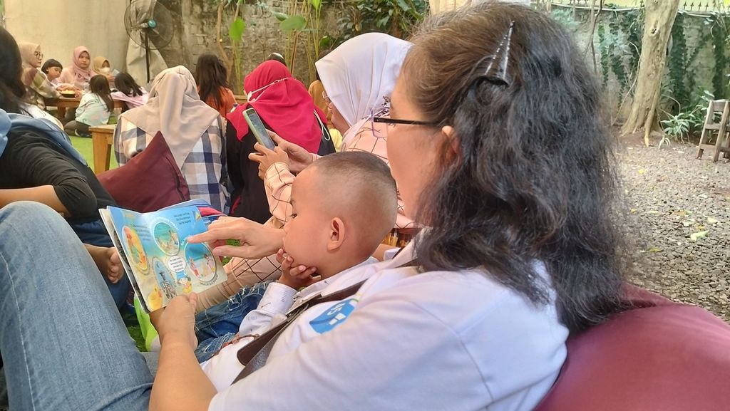 Seorang pendamping membacakan kisah dari buku cerita kepada salah satu anak dalam acara bertajuk membaca dan menulis bersama di kawasan Cibubur, Kecamatan Ciracas, Jakarta Timur, Minggu (29/1/2023).