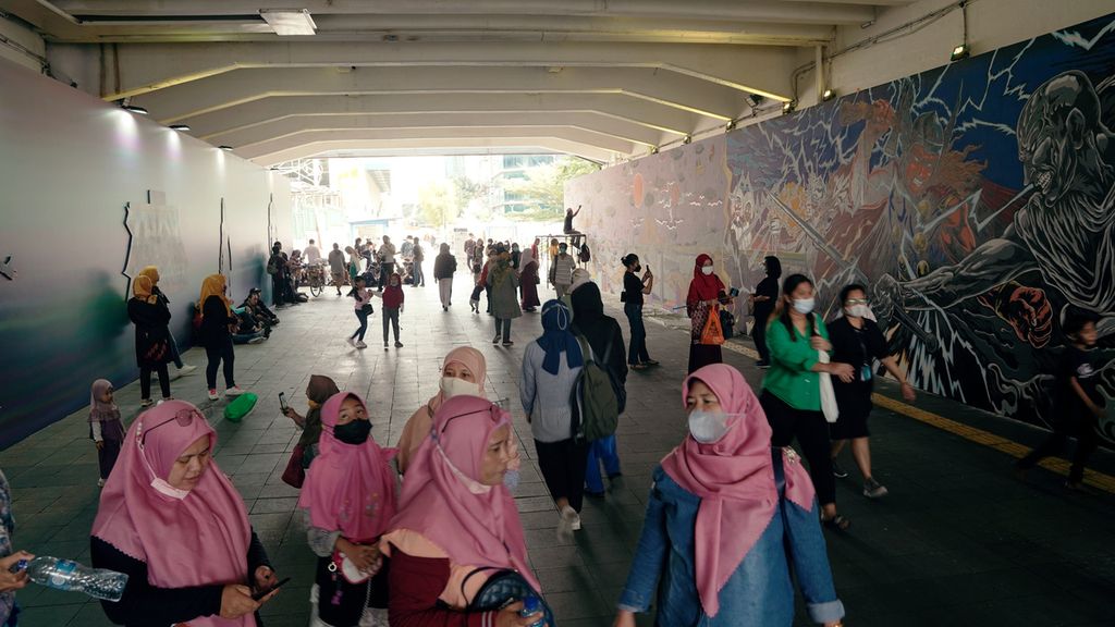 Warga melintasi mural kolaborasi di Terowongan Kendal, Kawasan TOD Dukuh Atas, Jakarta Pusat, Selasa (5/7/2022).